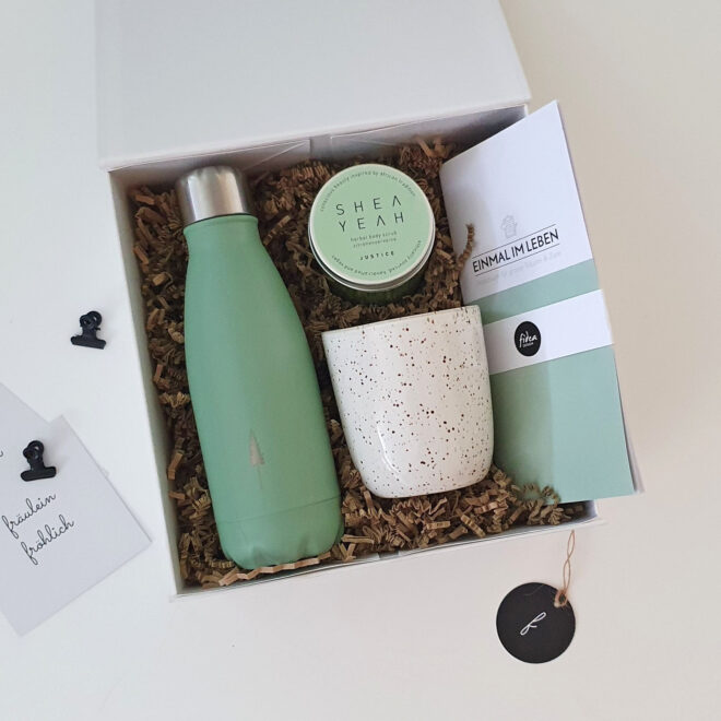grüne Geschenkbox mit Trinkflasche, Trinkbecher, Körperpeeling und Notizbuch