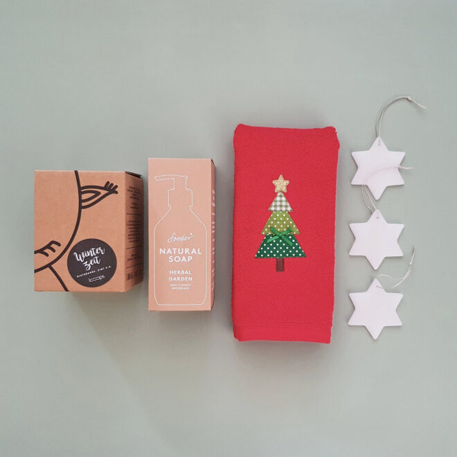 weihnachtliche Geschenkbox mit rotem Gästehandtuch, Kerze, Handseife und Wachssternen
